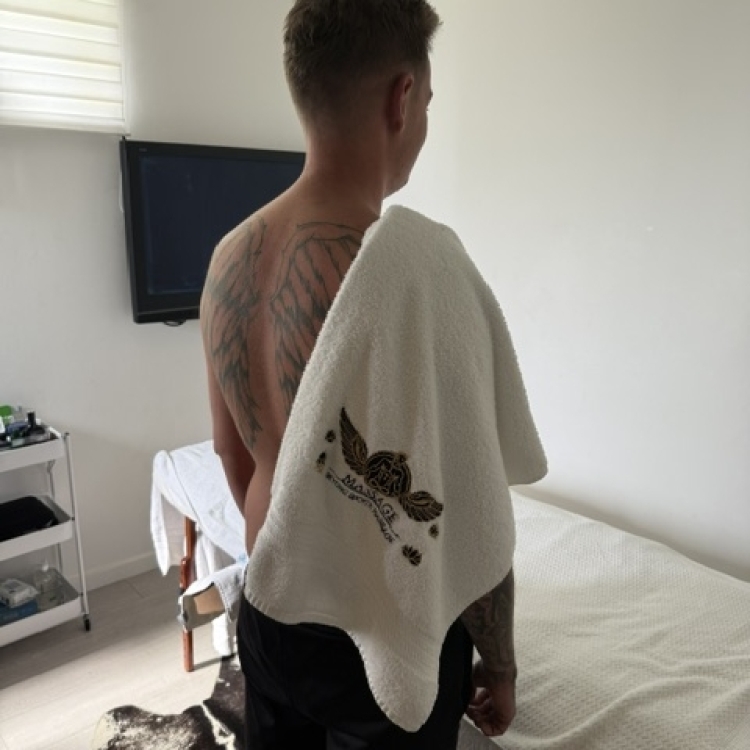 Client with tshirt off and back to camera with a towel with my logo drapsed over shoulder
