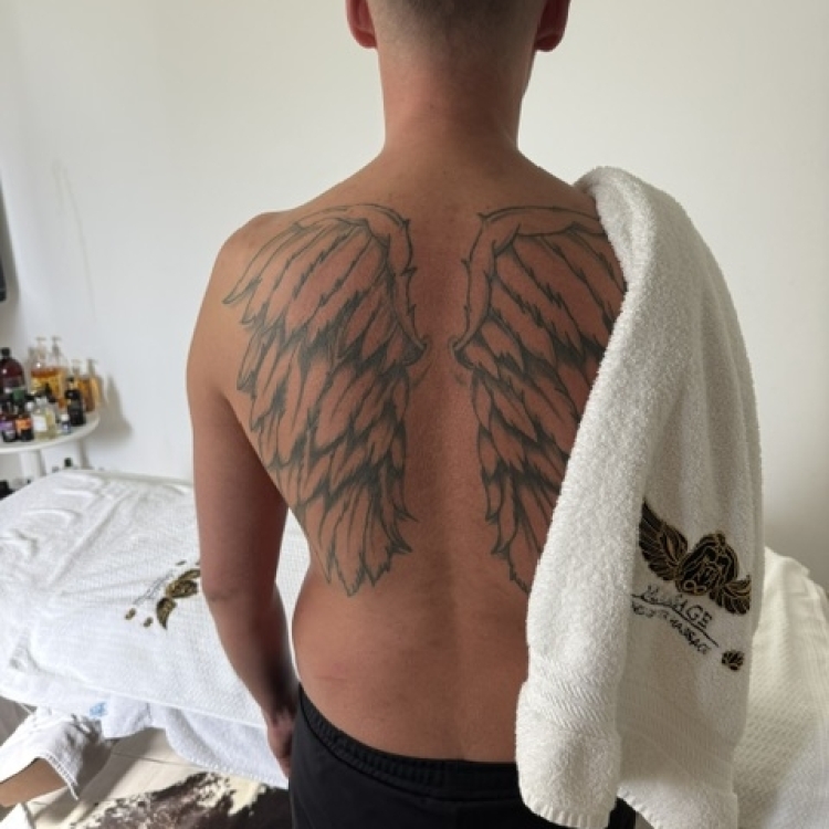 Client with tshirt off and back to camera with a towel with my logo drapsed over shoulder