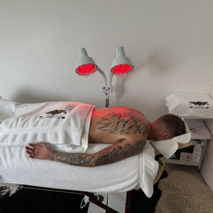 Client with angel wings tattoo face down on my massage bed and towel over bottom half of body