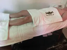 A client lying on my massage bed on their back with a towel over them