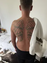 Client with tshirt off and back to camera with a towel with my logo drapsed over shoulder